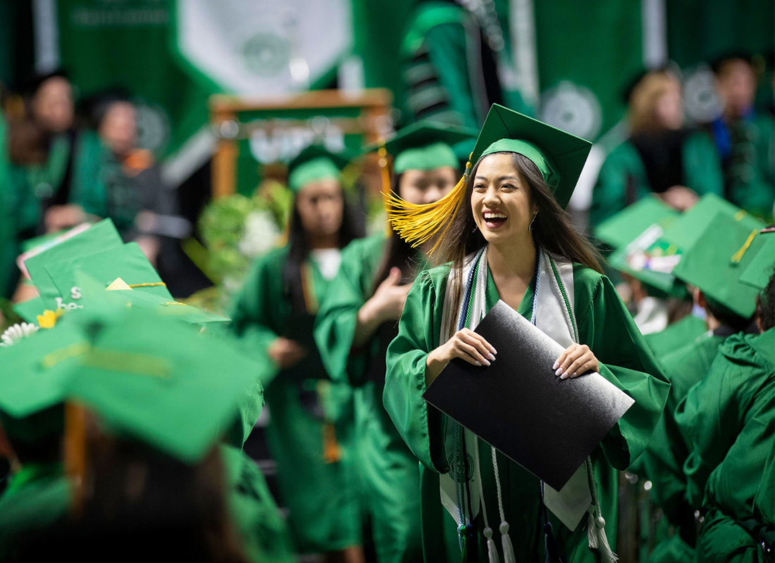 UNT student at graduation holding a diploma.